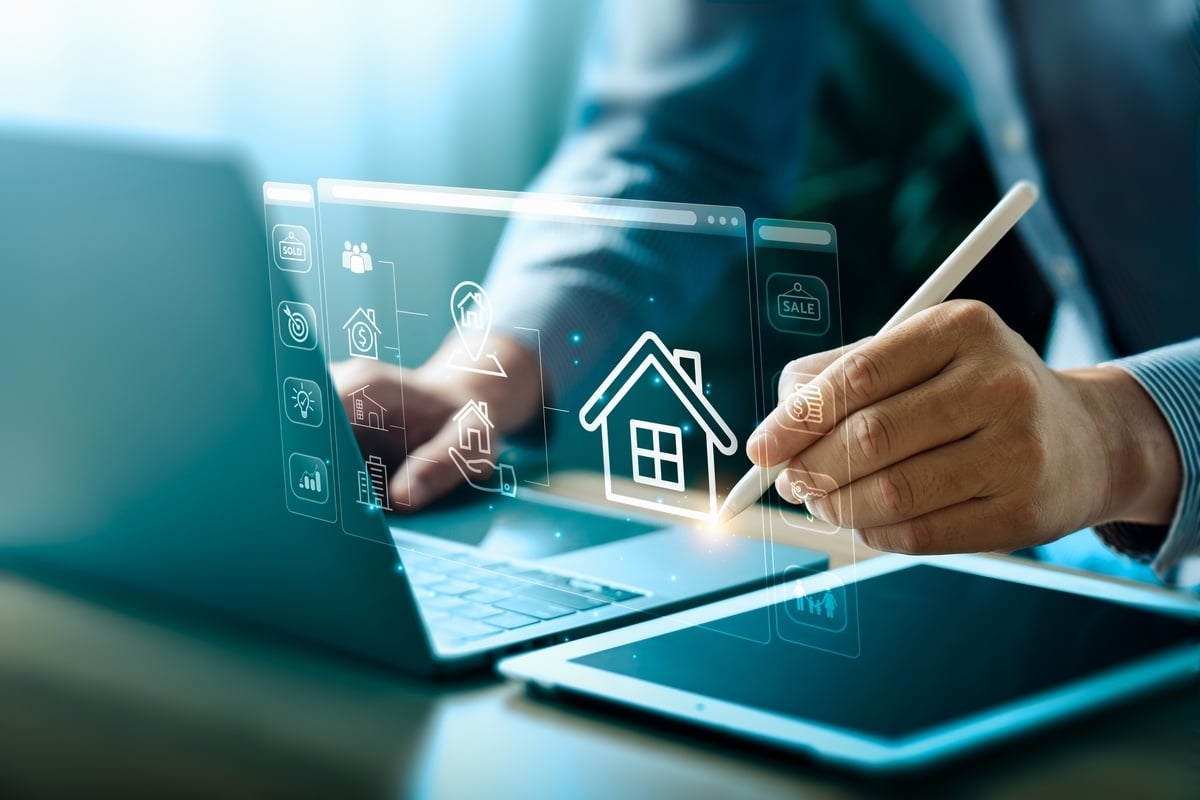 A man in a suit working on a laptop with house and other real estate icons