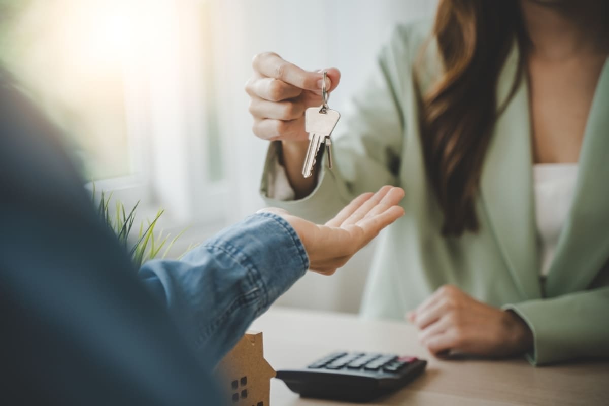 A property manager gives a tenant a key to their new home, demonstrating how to screen tenants for the rental property concept