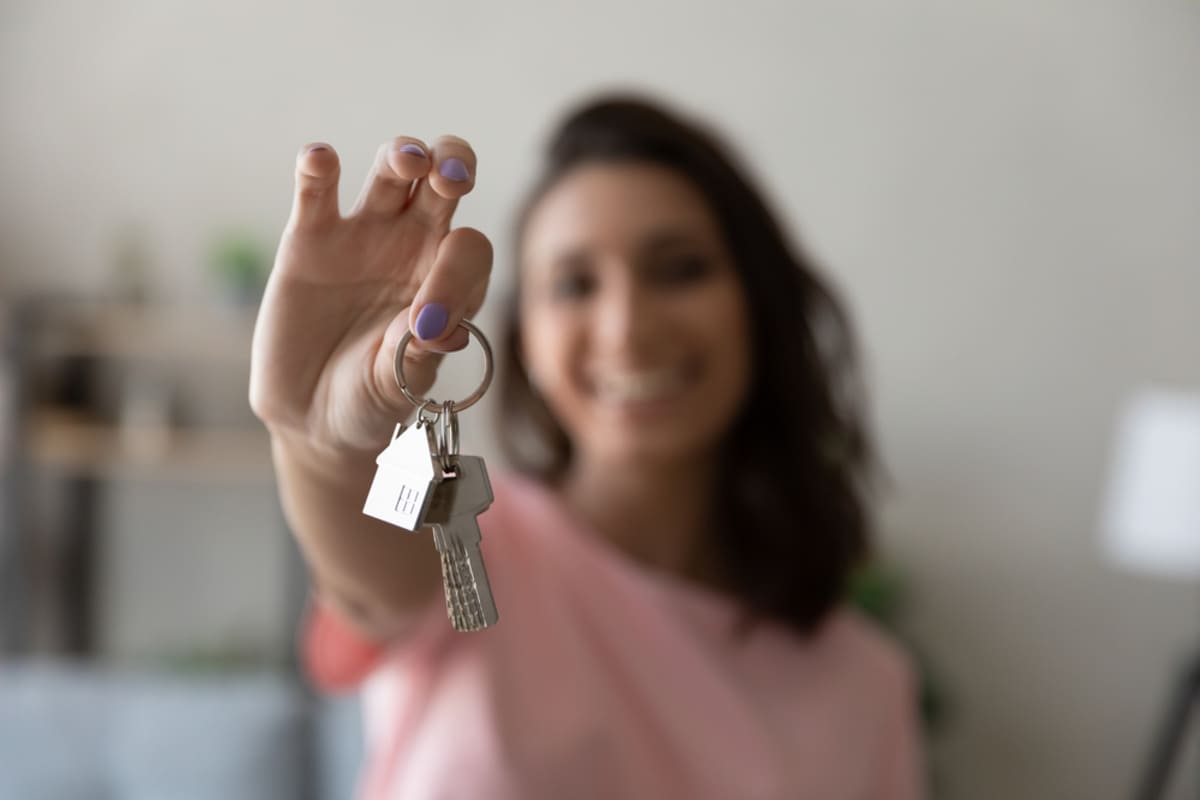 A woman holding keys to her new home, tenant satisfaction concept