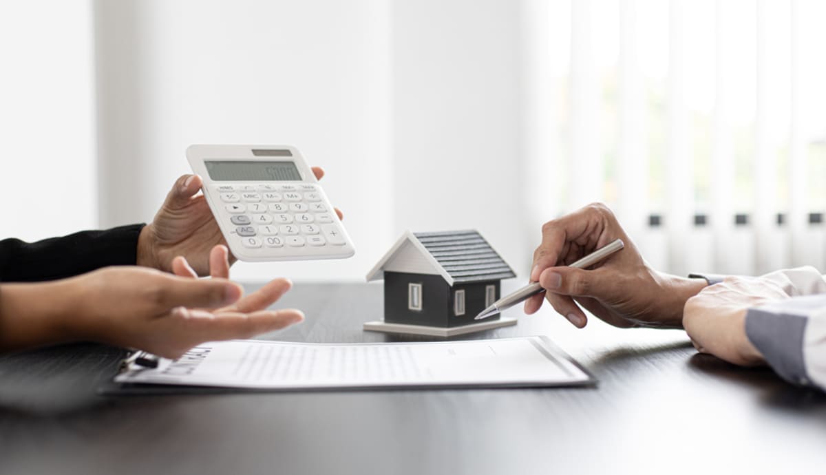 Two people discussing a small house and a contract with a calculator, Seattle rental market trends concept