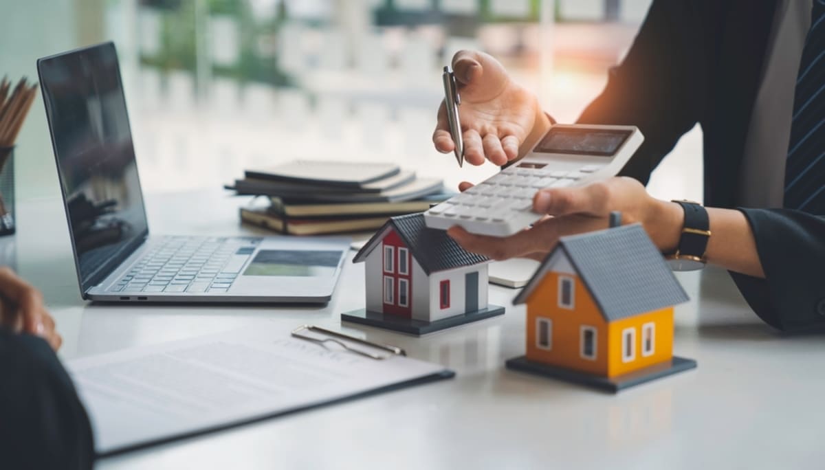 Two people discussing homes with a calculator and contract on the table, Seattle real estate investment concept