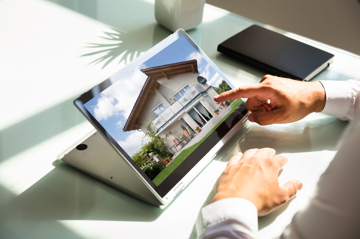 Close-up of businessman's hand checking house on laptop