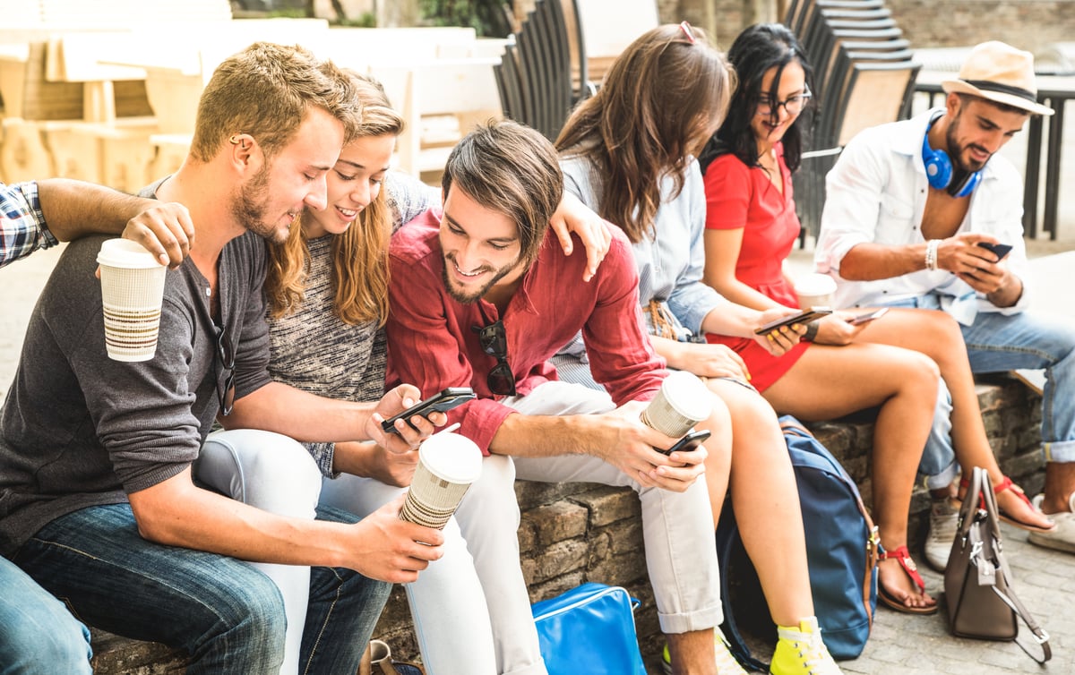 Multiracial millennials group using smart phone at city college backyard - Young people addicted by mobile smartphone - Technology concept with connected trendy friends - Warm vibranc