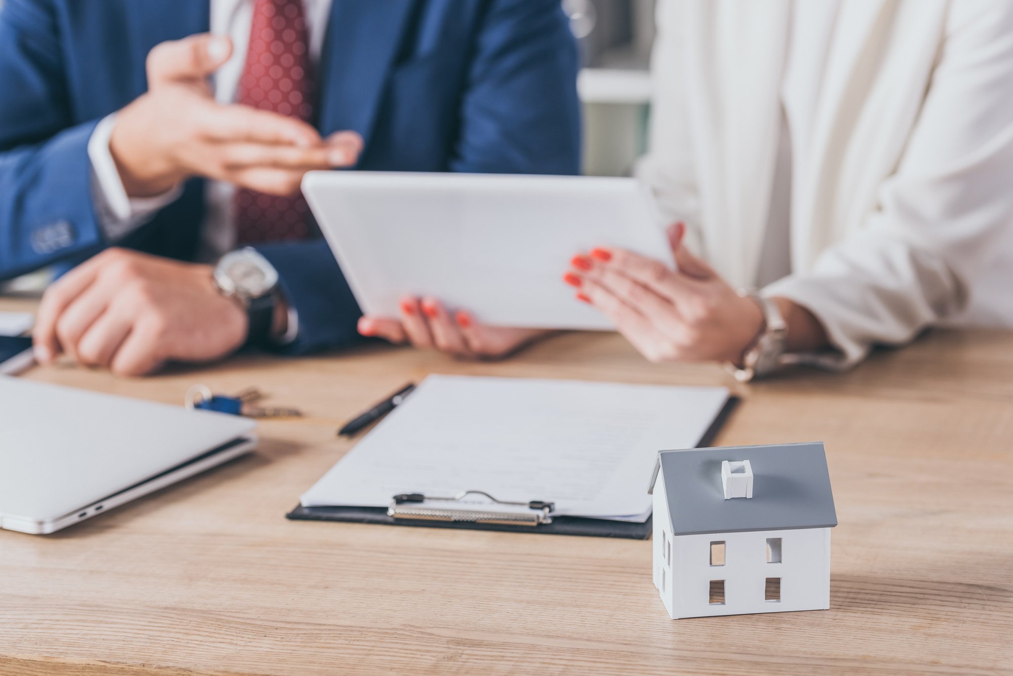 Selective focus of house model near woman holding digital tablet and businessman pointing with hand