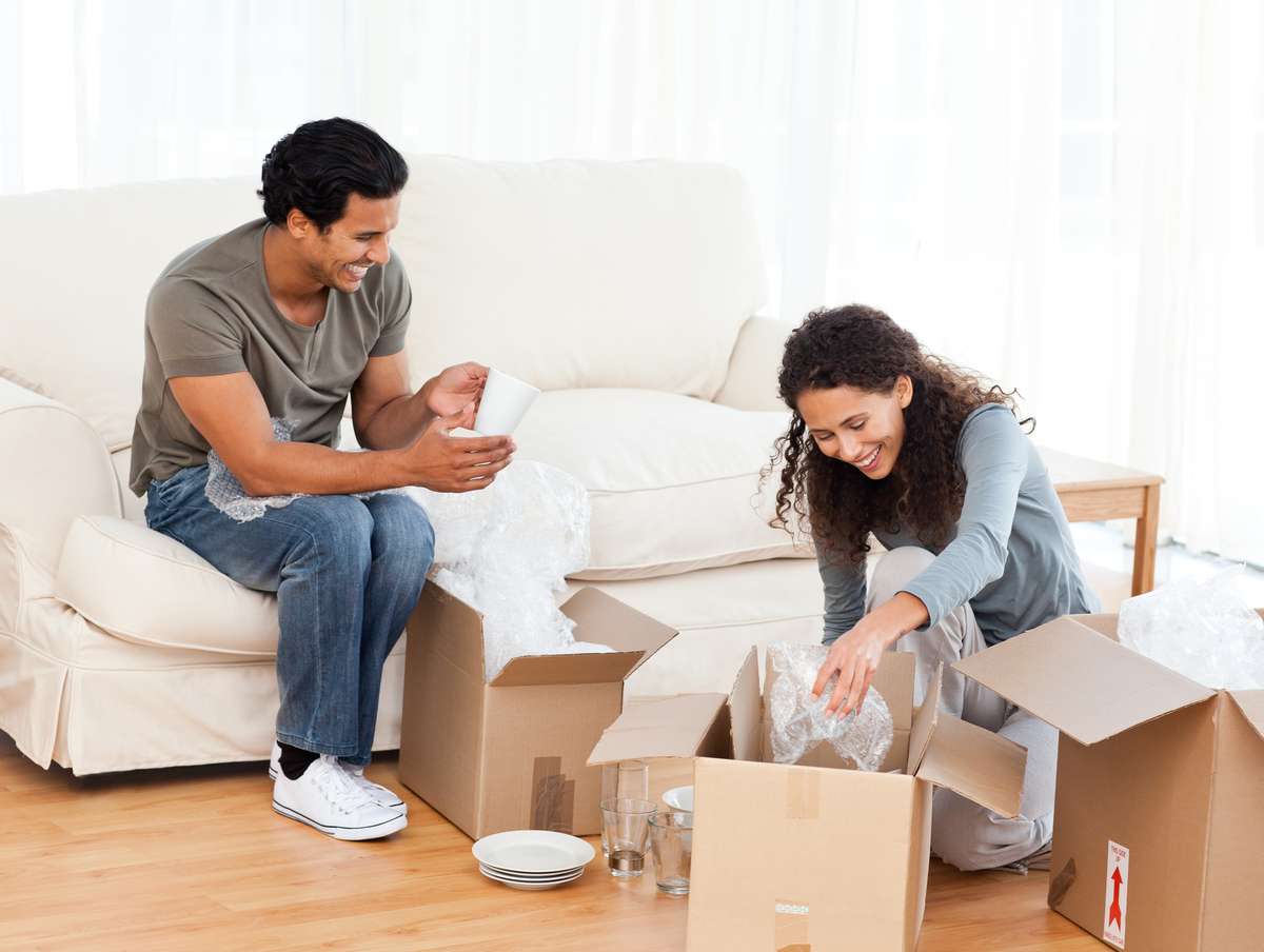 Happy couple packing glasses together in the living-room