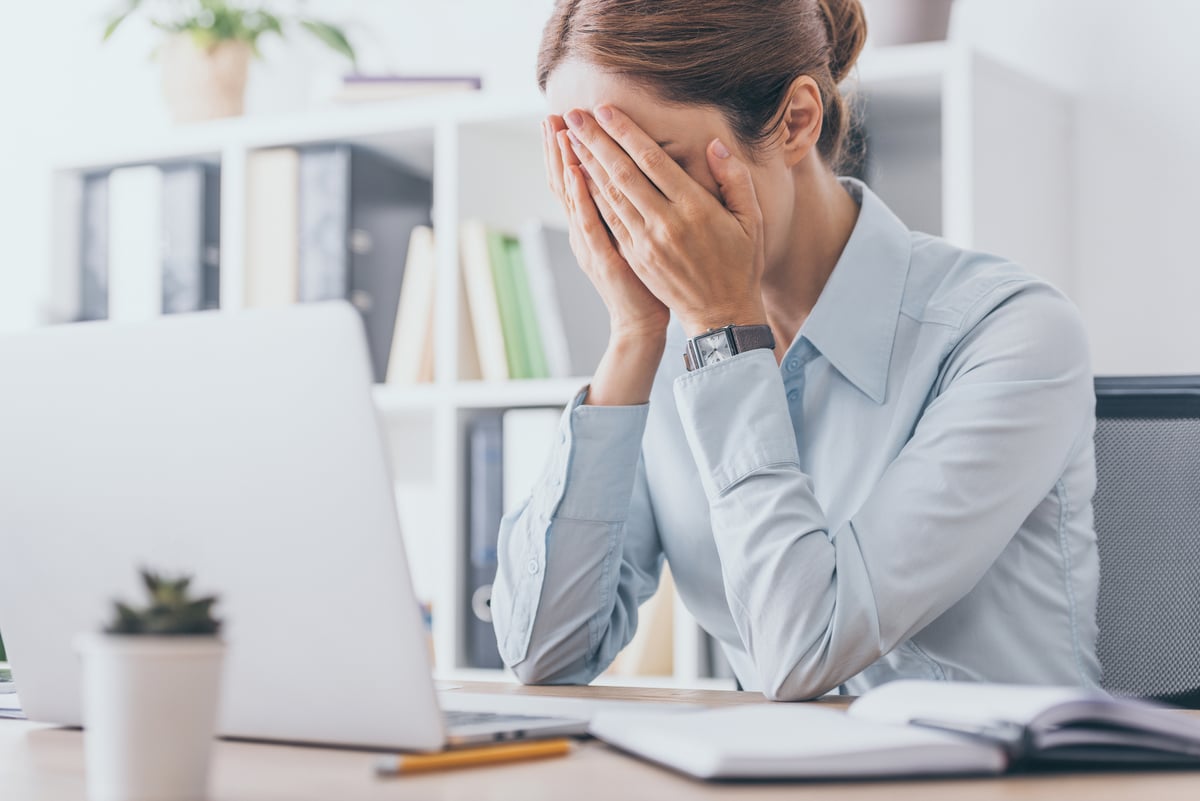 Stressed adult businesswoman covering face with hands at office