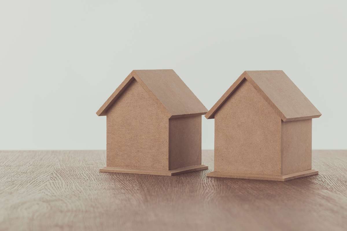 Two small wooden houses on wooden tabletop, saving concept (R) (S)