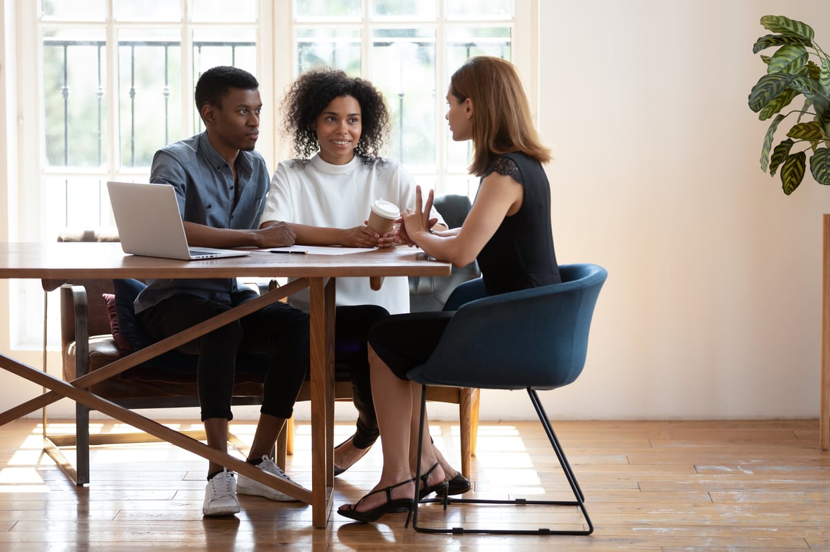 Young biracial couple consulting talking with female designer at meeting — Stock Image