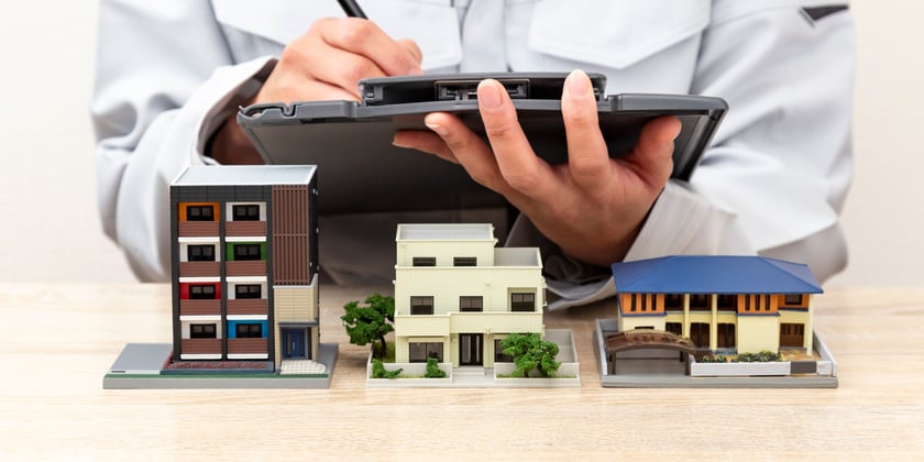 Man holding a clipboard over miniature houses