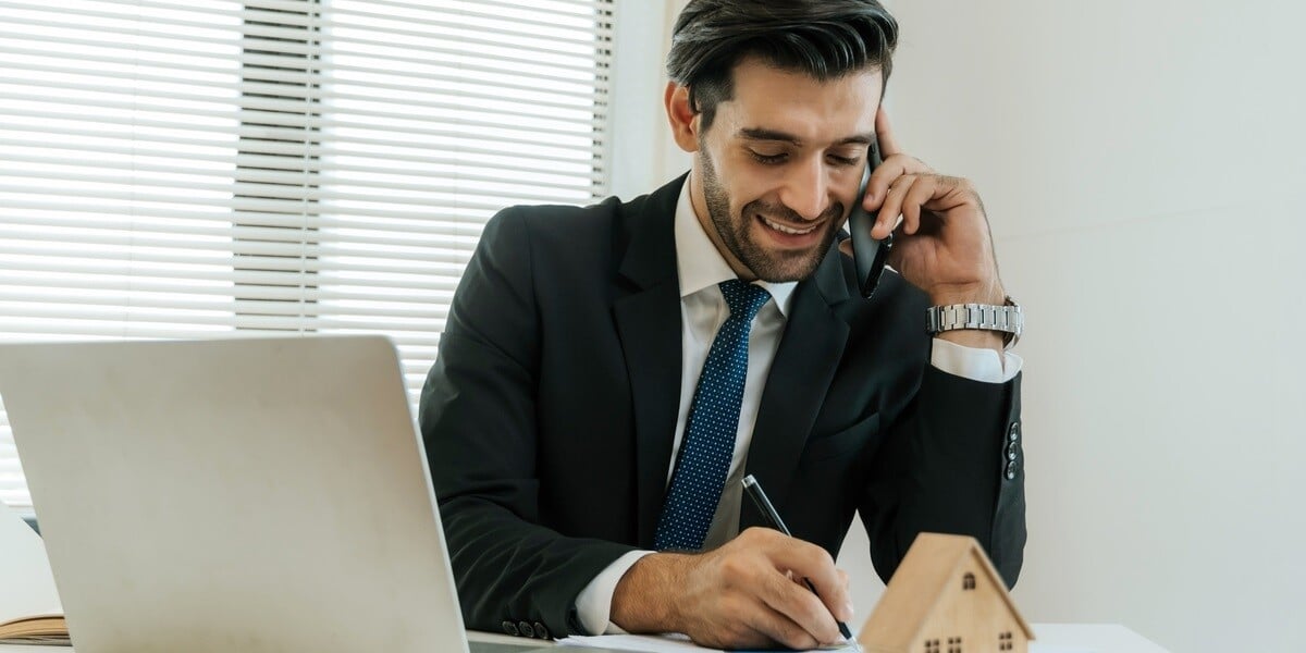 A businessman on the phone next to a model home