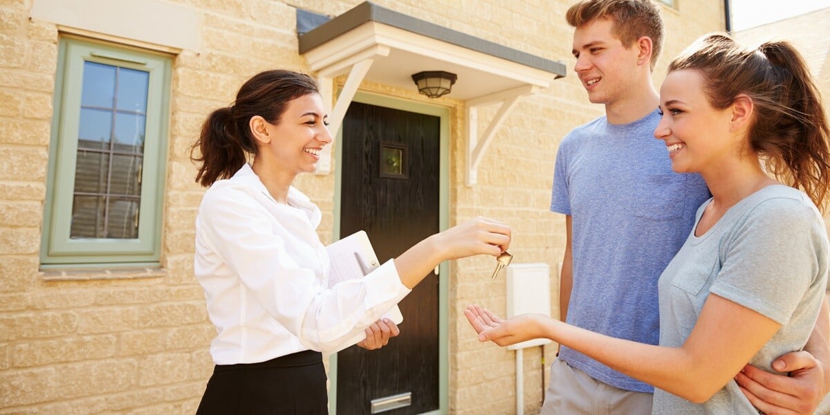 A landlord handing keys to a couple in their new home