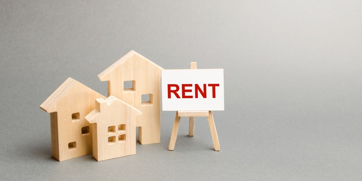 A sign that says  rent next to wooden model homes