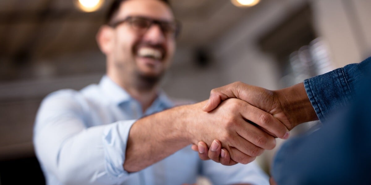 Two people shaking hands and smiling